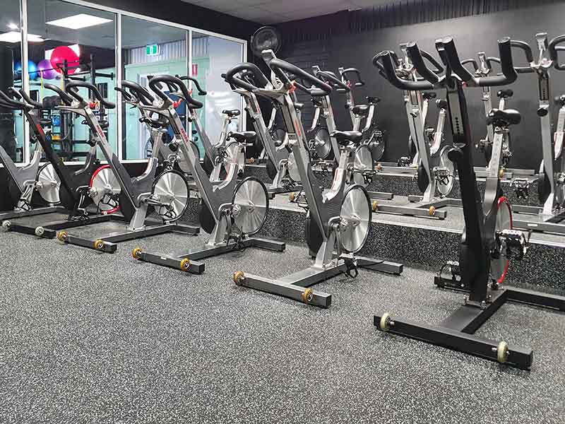Close up shot of spin room cycles on a rubber gym floor