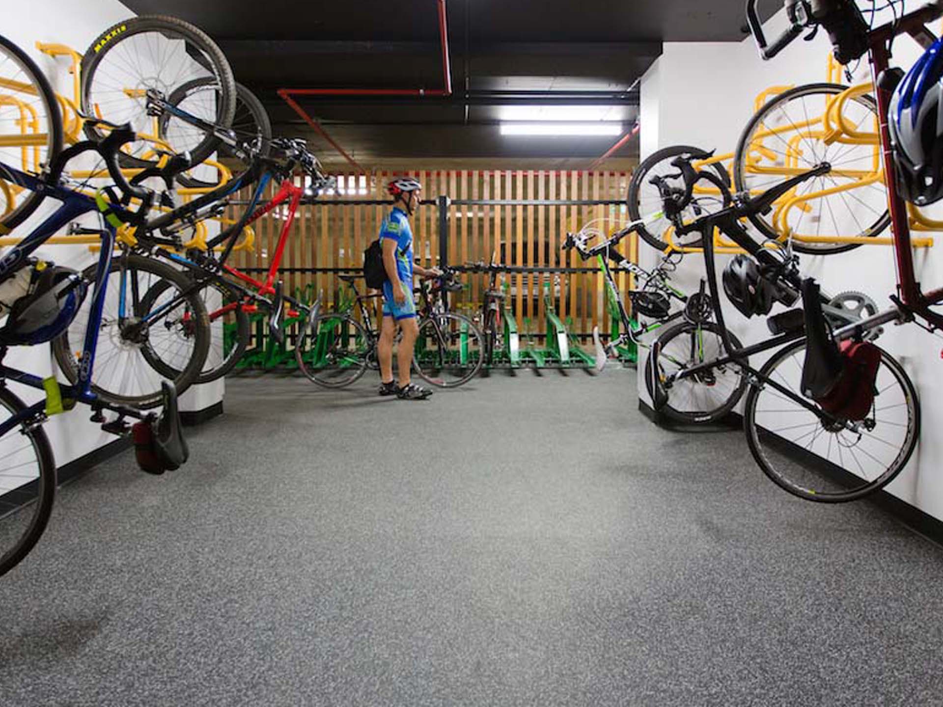 End-of-trip facility with rubber flooring, bikes and cyclist wearing cycling shoes.